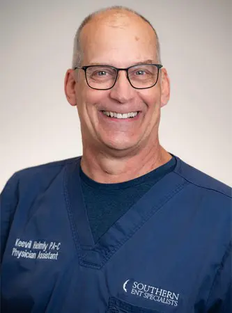 A man in glasses and blue shirt smiling for the camera.