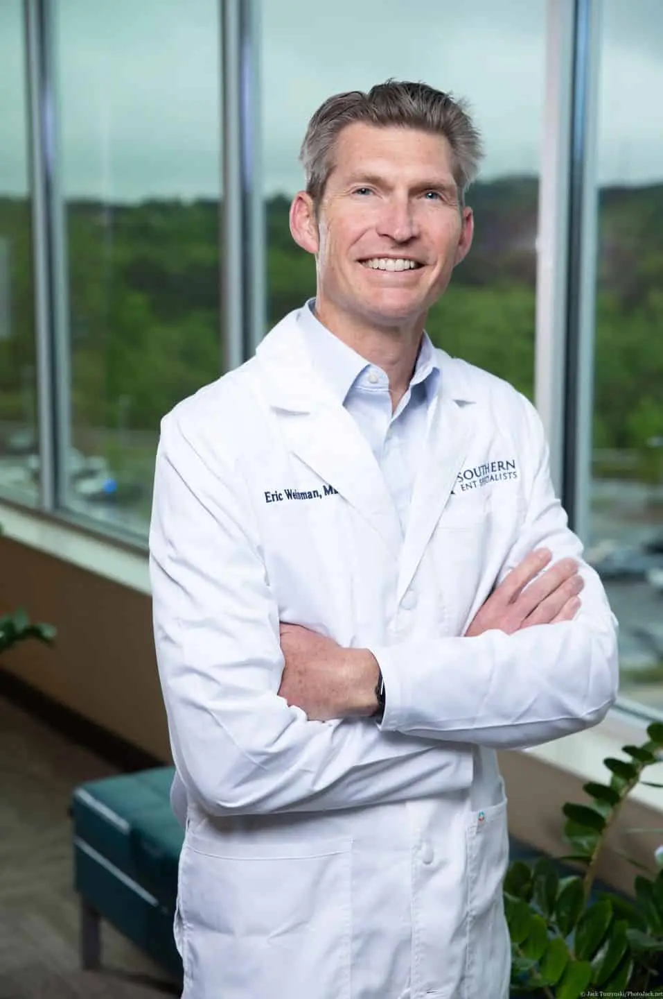 A man in white lab coat standing with his arms crossed.