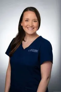 A woman in blue shirt smiling for the camera.