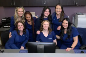 Group of women in blue uniforms smiling.